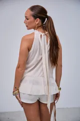 Blusa color crudo con escote halter y volados en el frente.