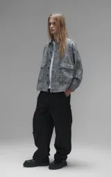 Campera de denim rígido con diseño de trama texturizada en tonos grises y negros. Presenta cuello camisero, cierre frontal con botones, mangas largas y dos bolsillos frontales con solapa.