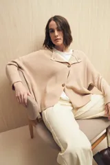 Sweater color beige de tejido de punto con cruce irregular y botones a contraste.