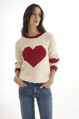 Buzo de lana merino tejido a mano, de color crema con un gran corazón rojo en el centro. Presenta cuello redondo, puños y bordes en color rojo contrastante.