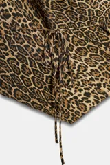Top halter de cuello fluido y bajo asimétrico, con estampado animal print tipo leopardo y cierre de lazos en la espalda.