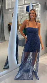 Vestido largo de fiesta color azul marino con diseño de brillos en patrón de hojas. Presenta un corte tipo strapless con breteles finos, una falda corta interior y una sobrecapa de tul transparente con tajo lateral.