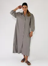 Vestido midi estilo camisero color gris, con cierre frontal de botones, cuello camisero, mangas largas abullonadas con detalles bordados y diseño holgado.