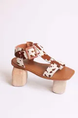 Sandalias planas con diseño de estampado animal print tipo vaca, con puntera cuadrada, tira en T y cierre con hebilla ajustable en el tobillo.