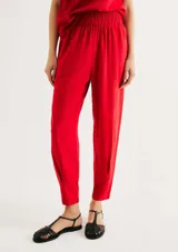 Pantalón de lino color rojo, de corte holgado y talle alto con cintura elástica fruncida. Presenta diseño recto que se estrecha ligeramente hacia los tobillos.
