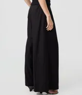 Pantalón de sastrería negro de modelado amplio, con pinzas frontales y cintura con pasadores.