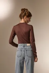 Body de manga larga con cuello a la base, confeccionado en poliamida, con ajuste al cuerpo y cierre inferior con broches.