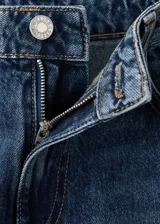 Jeans de corte recto y tiro medio en color azul clásico, con bolsillos delanteros y traseros, y cierre frontal con botón y cremallera.