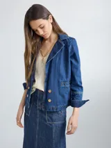 Chaqueta de jean azul oscuro, de corte corto y entallado, con cuello y solapa, y botones de madera en el frente.