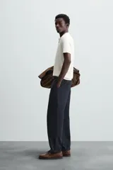 Polo de punto negro, manga corta, con cuello solapa y cierre frontal de tres botones. Presenta un calce regular y acabados en rib en mangas y ruedo.