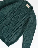 Sweater de lana merino color verde con diseño de trenzas en el frente.