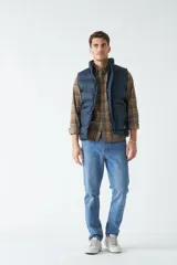 Chaleco color camel de nylon con cierre frontal con broches a presión, cuello alto y bolsillos laterales.