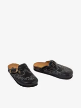 Mules negros de cuero con diseño vaquero y costura de águila en hilo blanco. Presentan hebilla lateral de ajuste y suela de corcho.