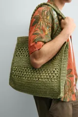 Bolso tipo shopper de color naranja con acabado trenzado y diseño estructurado. Cuenta con compartimento principal y dos asas cortas de mano.