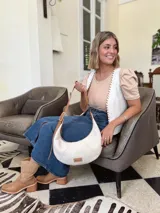 Cartera tipo hobo de cuero color crudo con correa de cuero marrón.