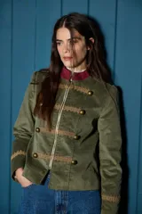 Blazer corto de estilo militar confeccionado en terciopelo azul marino, con cuello mao, cierre frontal con cremallera, detalles de galones bordados y botones metálicos decorativos.
