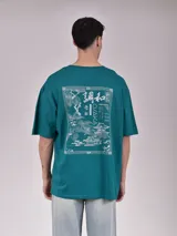 Remera color verde petroleo, de manga corta y corte oversize, con estampa en el pecho izquierdo que dice 'Noble Origins' junto a un diseño floral.