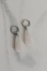 Aros tipo argolla de acero quirúrgico con dije colgante en forma de gota de piedra natural en tono marrón.
