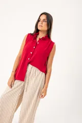 Camisa roja sin mangas con cuello mao adornado con un volado y cierre frontal con botones.