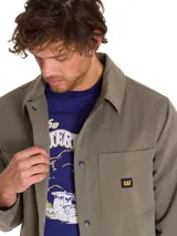 Chaqueta tipo coach de color verde oliva, con cierre frontal a presión, cuello camisero, puños elásticos y múltiples bolsillos frontales. Incluye etiqueta con logo de la marca en el pecho.