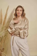 Blusa de satén color champagne con cuello a la base, mangas anchas y puños elásticos con detalle bordado.