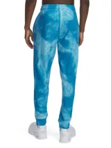 Pantalón de jogging Under Armour con estampado tie-dye en tonos azules. Presenta cintura elástica con cordón ajustable, bolsillos laterales y puños elásticos en los tobillos. Incluye el logo de la marca bordado en la parte superior derecha.