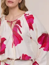 Conjunto de dos piezas de crep compuesto por una blusa holgada con escote en V y mangas largas abullonadas, y un pantalón palazzo tiro alto con pretina elástica. Presenta un estampado floral en tonos rosados sobre base blanca.