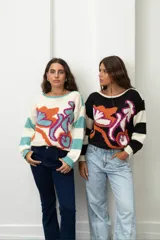 Buzo de tejido de punto con diseño estampado de flores abstractas y mangas a rayas. Presenta cuello redondo y corte holgado.