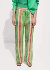 Pantalon de corte recto y tiro medio, confeccionado en tejido fluido semitransparente con estampado de rayas verticales en tonos verdes, rojos y amarillos. Presenta cintura elástica con cierre de lazo ajustable.