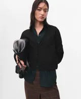 Cardigan de punto fino color negro, con cuello en V, manga larga y cierre frontal de botones.