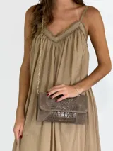 Bandolera de cuero color crudo con textura tipo piel de cocodrilo, con correa de cadena dorada.