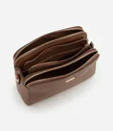 Bolso bandolera de tamaño mediano confeccionado en poliuretano color marrón. Presenta tres compartimentos independientes con cierre de cremallera, herrajes metálicos dorados y una correa de hombro ajustable de cinta tejida bicolor.