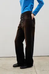 Pantalón de tiro alto confeccionado en pana, con corte recto y efecto gastado en degradé que transiciona de tonos oscuros a ocre. Presenta un cierre frontal con botones visibles y costuras a contratono.