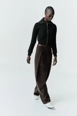 Chaqueta de felpa negra con cuello solapa, manga larga con puño, bolsillos de plastrón en el delantero y cierre frontal con cremallera.