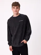 Sweater de cuello redondo y manga larga con diseño de hombros raglán, confeccionado en tejido de punto acanalado con efecto lavado. Presenta un pequeño logo bordado en el pecho.
