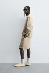 Bermuda de algodón color beige, estilo jogger, con corte relajado, cintura elástica ajustable con cordón y bolsillos laterales y trasero.