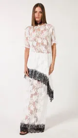 Blusa de encaje blanco con diseño floral transparente, cuello redondo y mangas cortas de corte relajado.