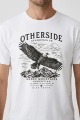 Remera blanca de manga corta y cuello redondo, confeccionada en algodón, con estampa frontal de un águila volando sobre montañas y la inscripción "Otherside Expedition Co. Andes Mountains Argentina".