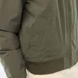 Campera estilo bomber color verde militar, con cierre frontal, cuello, puños y ruedo de tejido elástico acanalado. Presenta un bolsillo con cierre en la manga izquierda.