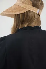 Camisa de lino color beige, de silueta romántica con escote a la base y mini volado. Cuenta con mangas 3/4 abullonadas con frunces y terminación en elástico. Posee detalles de puntillas negras en contraste en el frente y cierre frontal con botones ocultos bajo cartera.