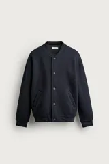 Chaqueta relaxed fit de color negro, confeccionada en tejido de canalé con mezcla de lana. Presenta cuello redondo, puños y dobladillo en rib elástico, bolsillos frontales de vivo y cierre con botones a presión.