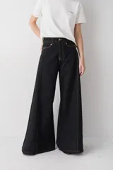 Jean de corte wide leg en color negro con costuras en contraste color ocre. Presenta cintura alta, cierre frontal con botón metálico y diseño de pierna ancha.