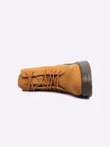 Borcego de gamuza color tostado, con cordones al tono y suela de goma dentada.