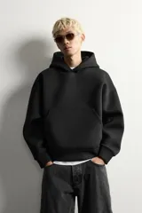 Sudadera negra de corte boxy fit, confeccionada en tejido compacto con elasticidad. Presenta capucha, manga larga, bolsillo frontal tipo canguro y acabados en rib.