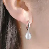 Aros de argolla plateados con dije colgante en forma de lágrima de piedra blanca iridiscente.