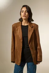 Blazer de gamuza color marrón, con cuello solapa, cierre frontal con un botón, bolsillos frontales tipo parche y diseño holgado.