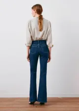 Jeans de denim azul oscuro con diseño flare, tiro alto, trabillas y cinco bolsillos.