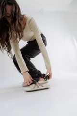 Pantalón de jean negro de corte recto y tiro alto, con detalle de botones en el dobladillo de la pierna.