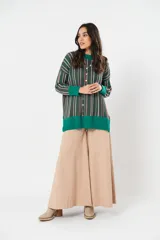 Sweater verde esmeralda de cuello redondo y manga larga, con terminación acanalada en puños y ruedo. Presenta tajos laterales y diseño de rayas verticales en tonos blanco y rosa.