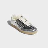 Championes Adidas Samba OG en acabado plateado metalizado, con detalles en color crema y suela de goma marrón translúcida.